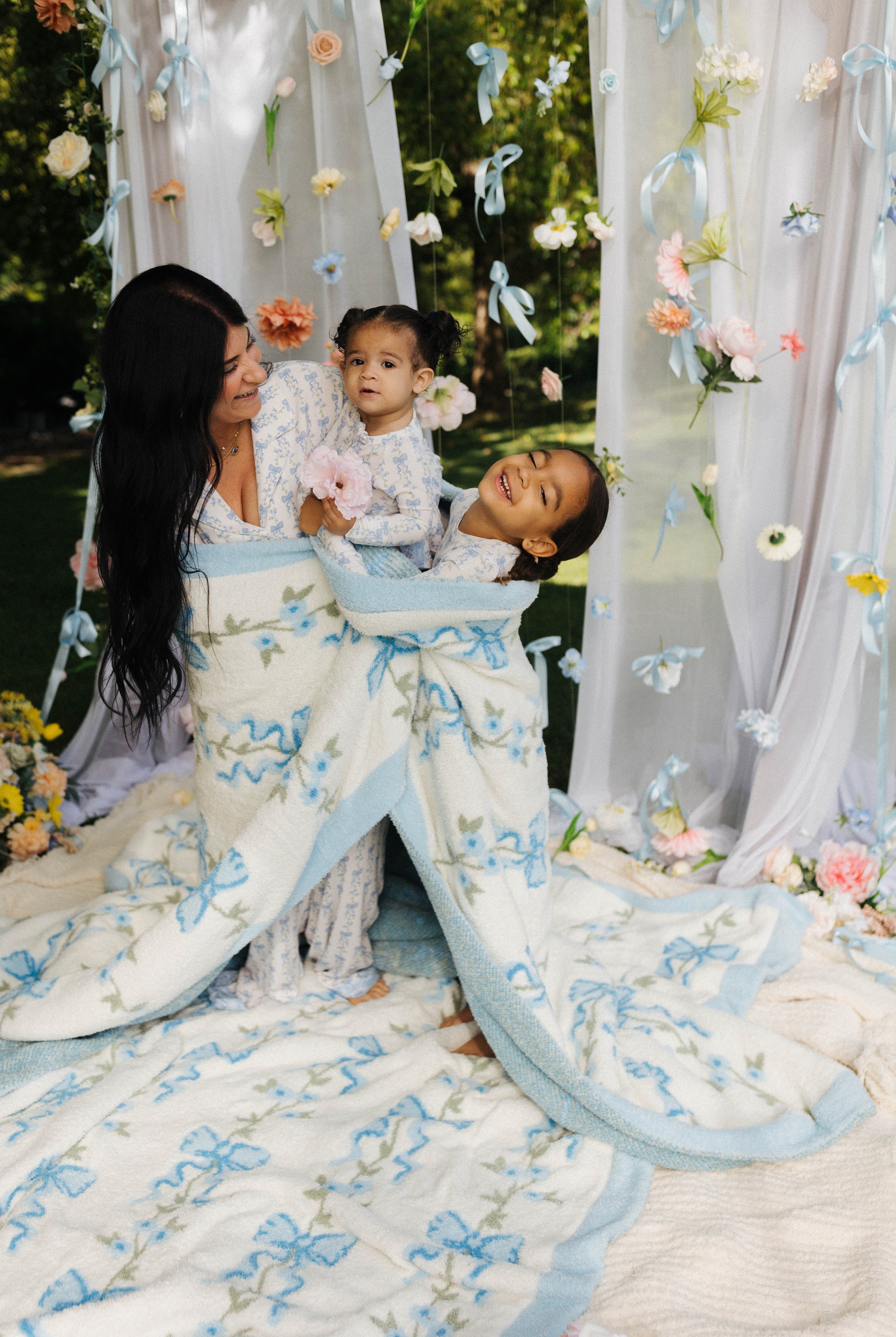two children and their mom snuggled up in floral bow blanket