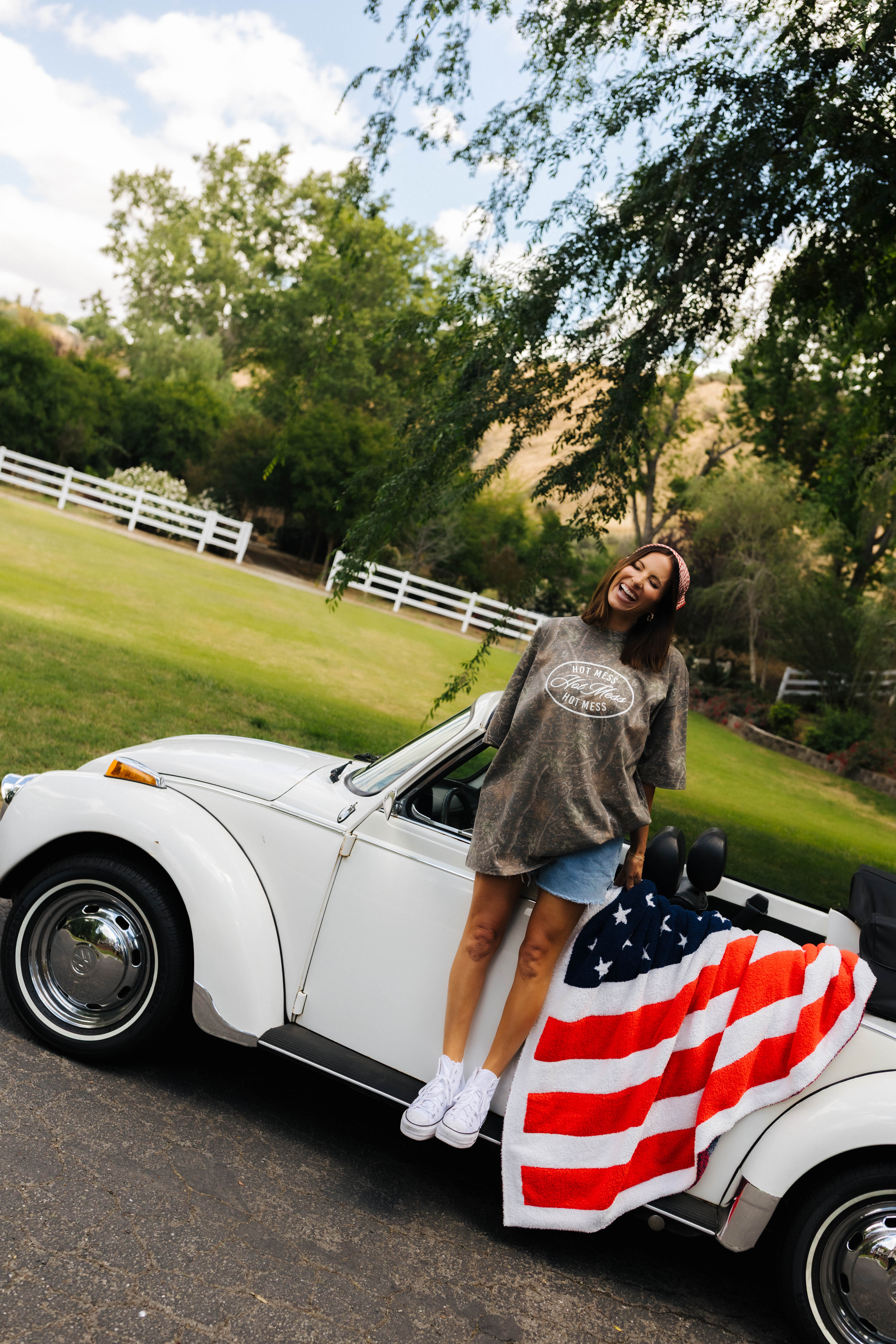 another photo of krista smiling on the bug with the american flag blanket styled on it
