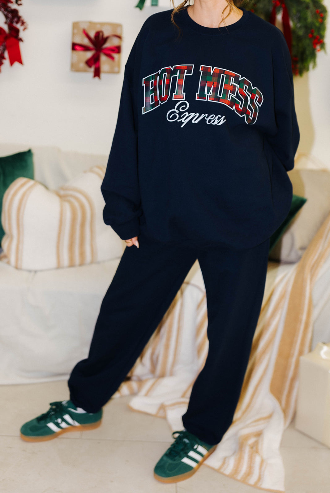 Person wearing a navy sweatshirt with 'HOT MESS Express' text in red and white, standing in a cozy living room.