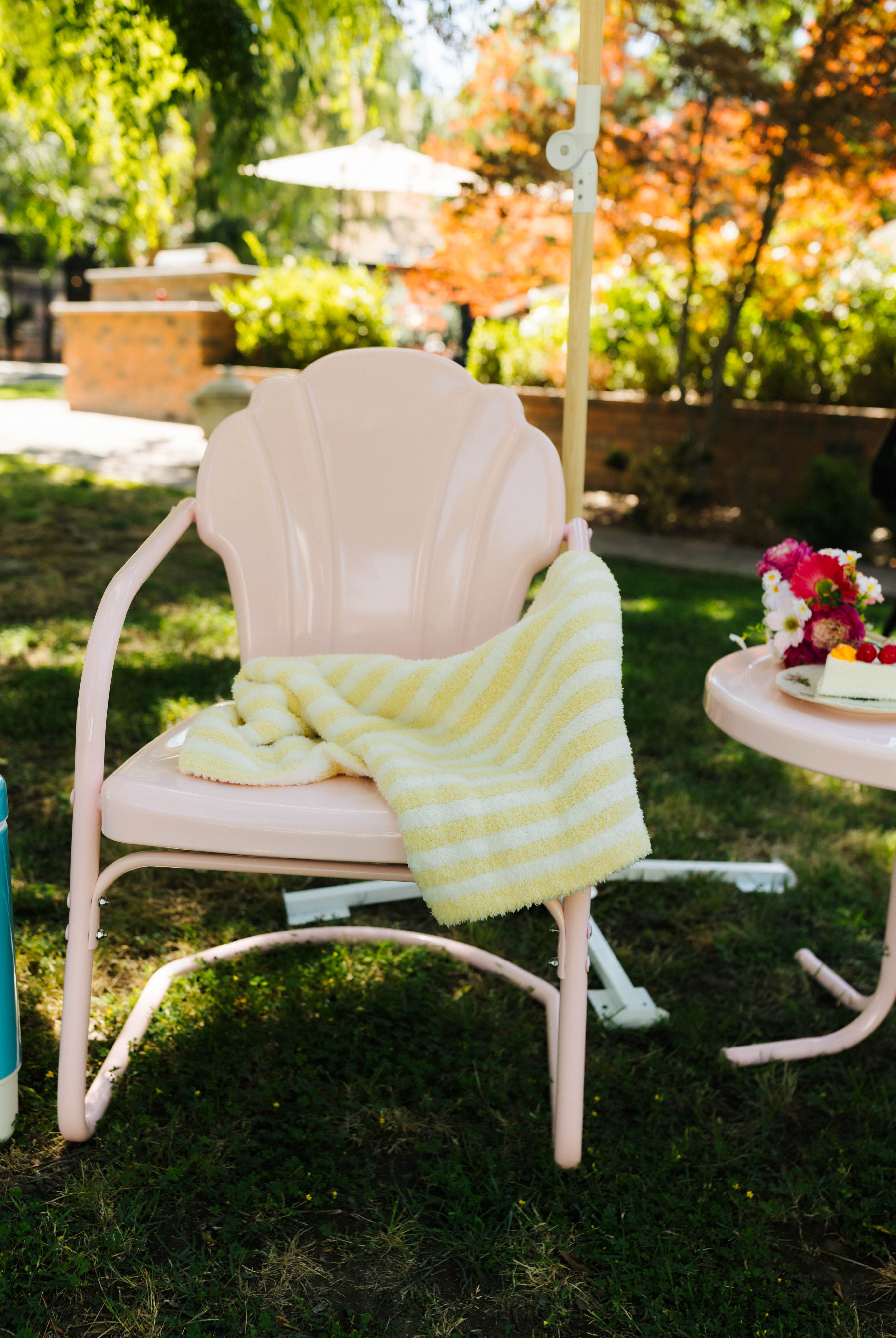 Pink chair with a yellow blanket in a garden setting