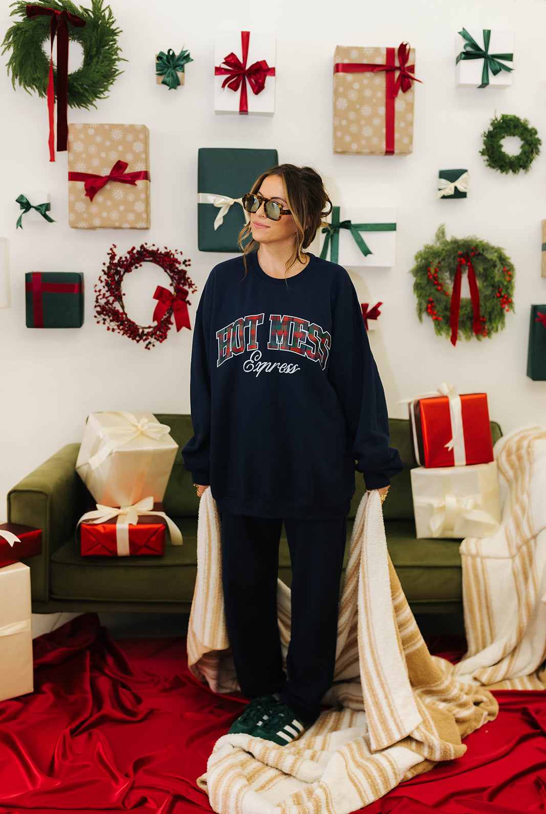 Person wearing a navy sweatshirt with text in a festive room with wreaths and presents.