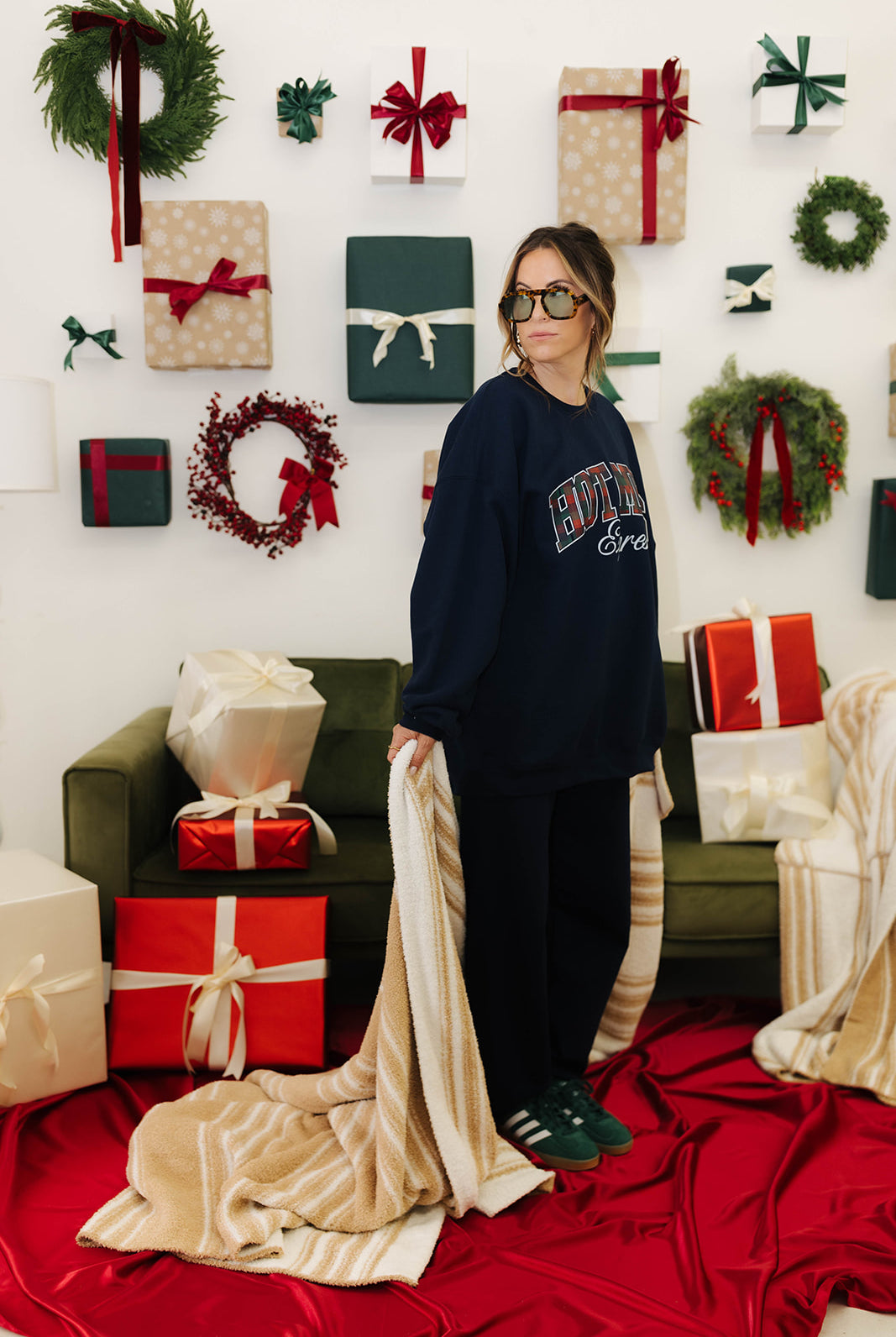 Person wearing a dark blue sweatshirt with text, standing in a festive room with Christmas decorations.