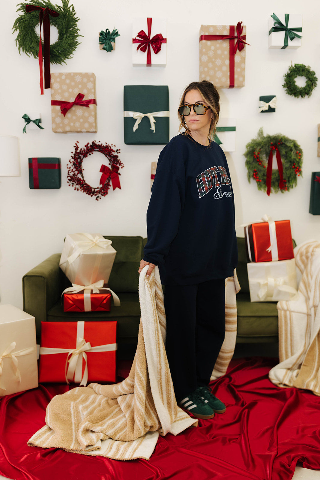Person wearing a dark blue sweatshirt with text, standing in a festive room with Christmas decorations.