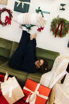 Person lying on a couch surrounded by Christmas presents and decorations.