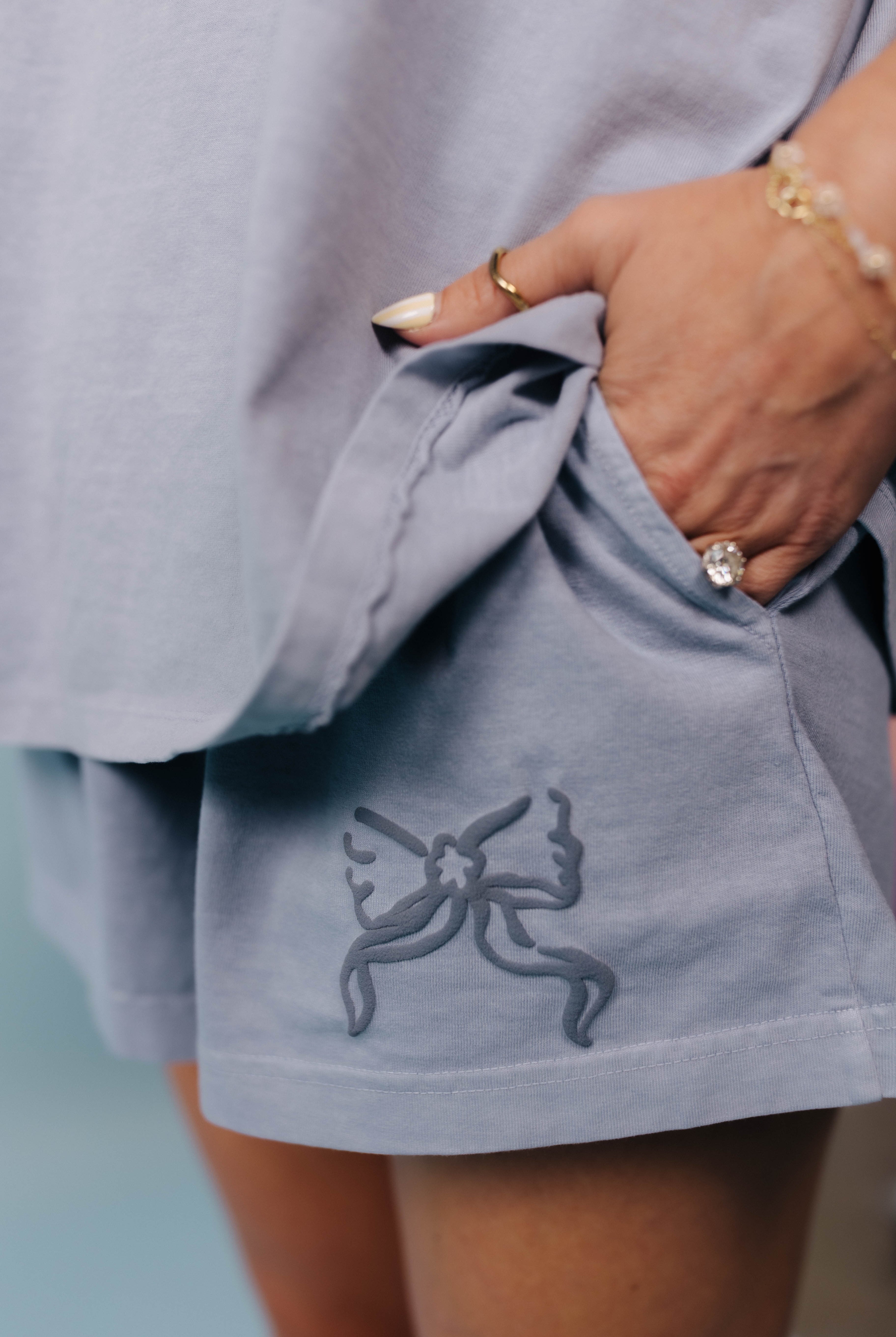 Light blue shorts with a bow logo beflore the pocket worn