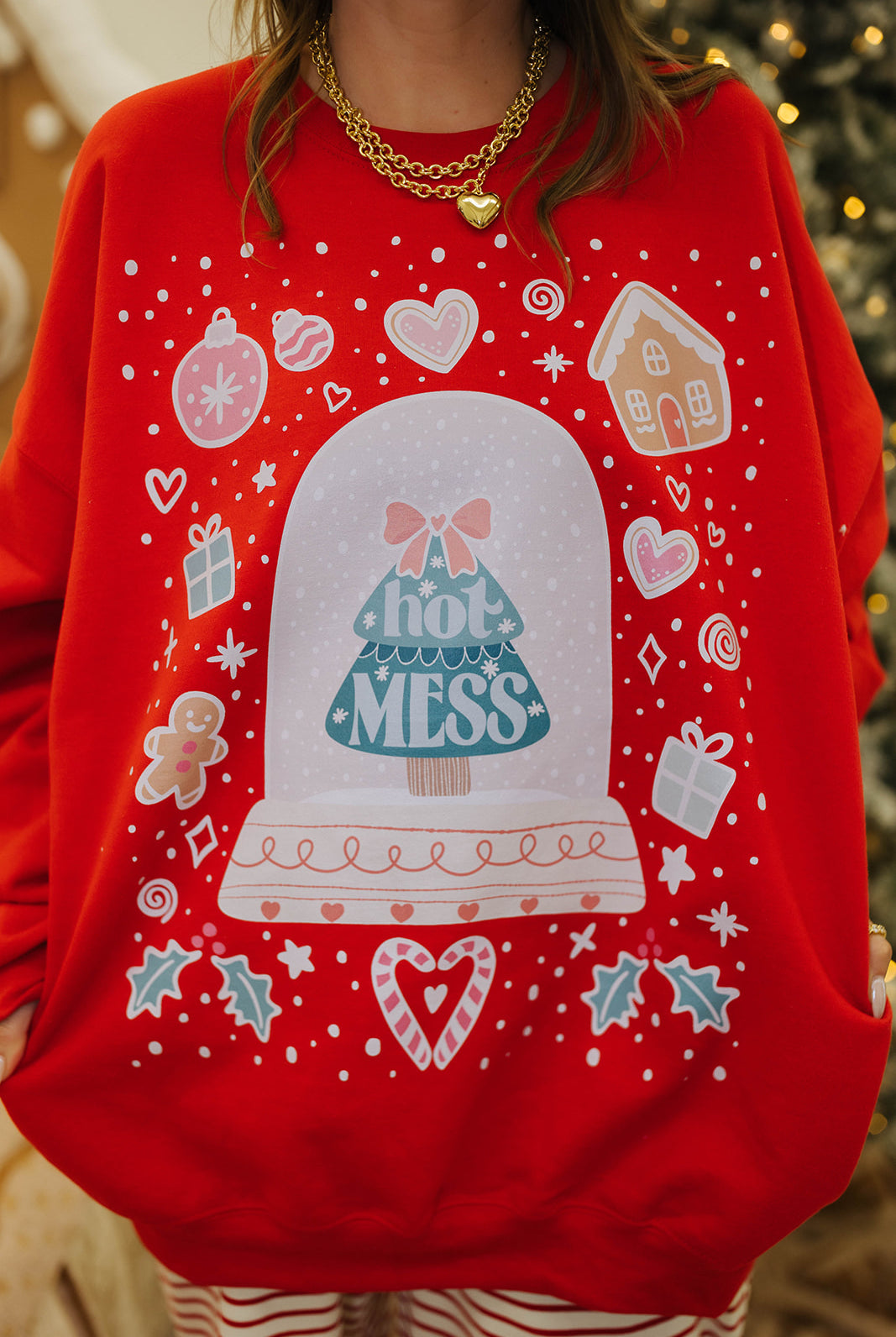 Red sweater with a snow globe design and 'Hot Mess' text, worn by a person.