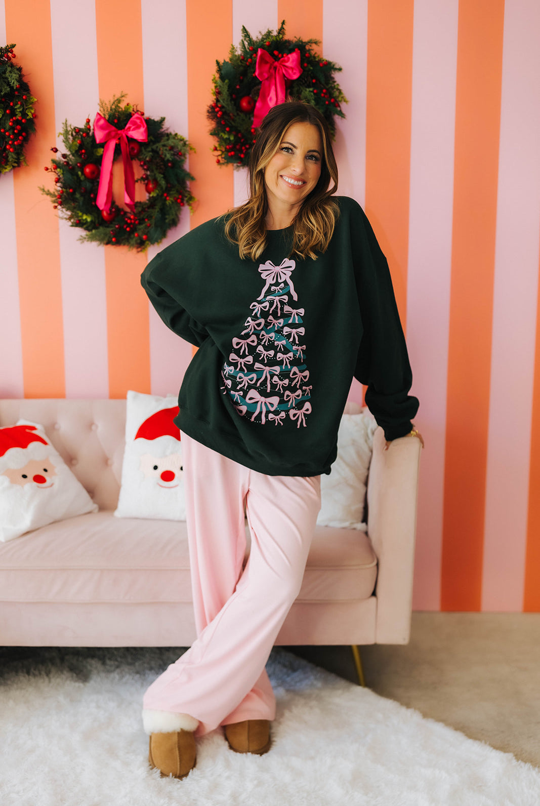 Woman wearing a festive sweater with a Christmas tree design in a room decorated for the holidays.