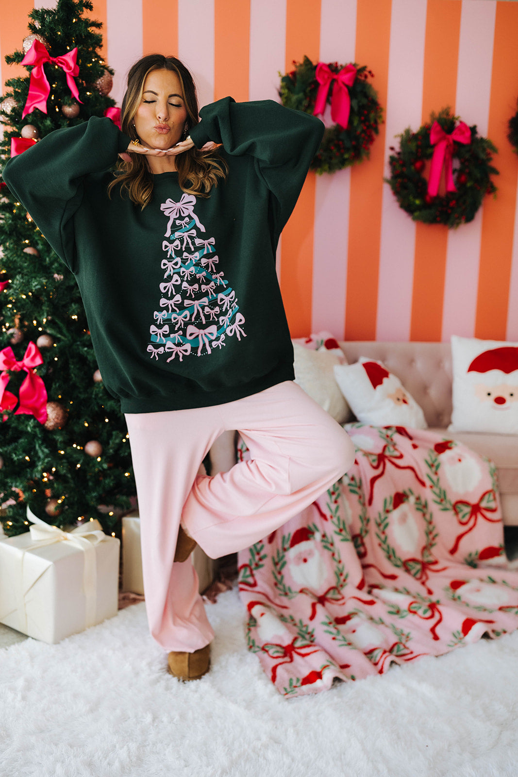 Person wearing a festive green sweatshirt with a Christmas tree design in a decorated room.