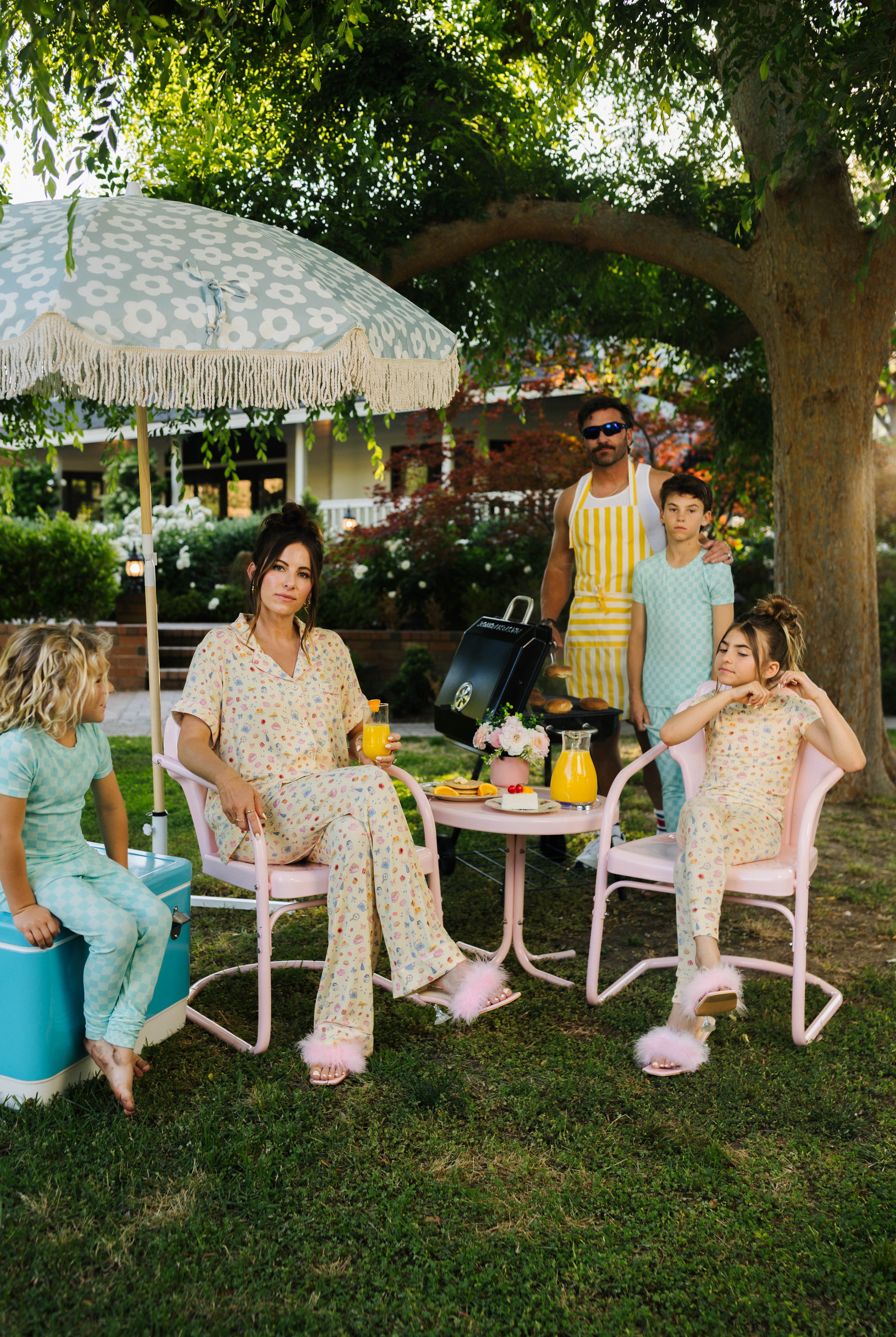 family outside grilling and sitting on chairs posing for the pj