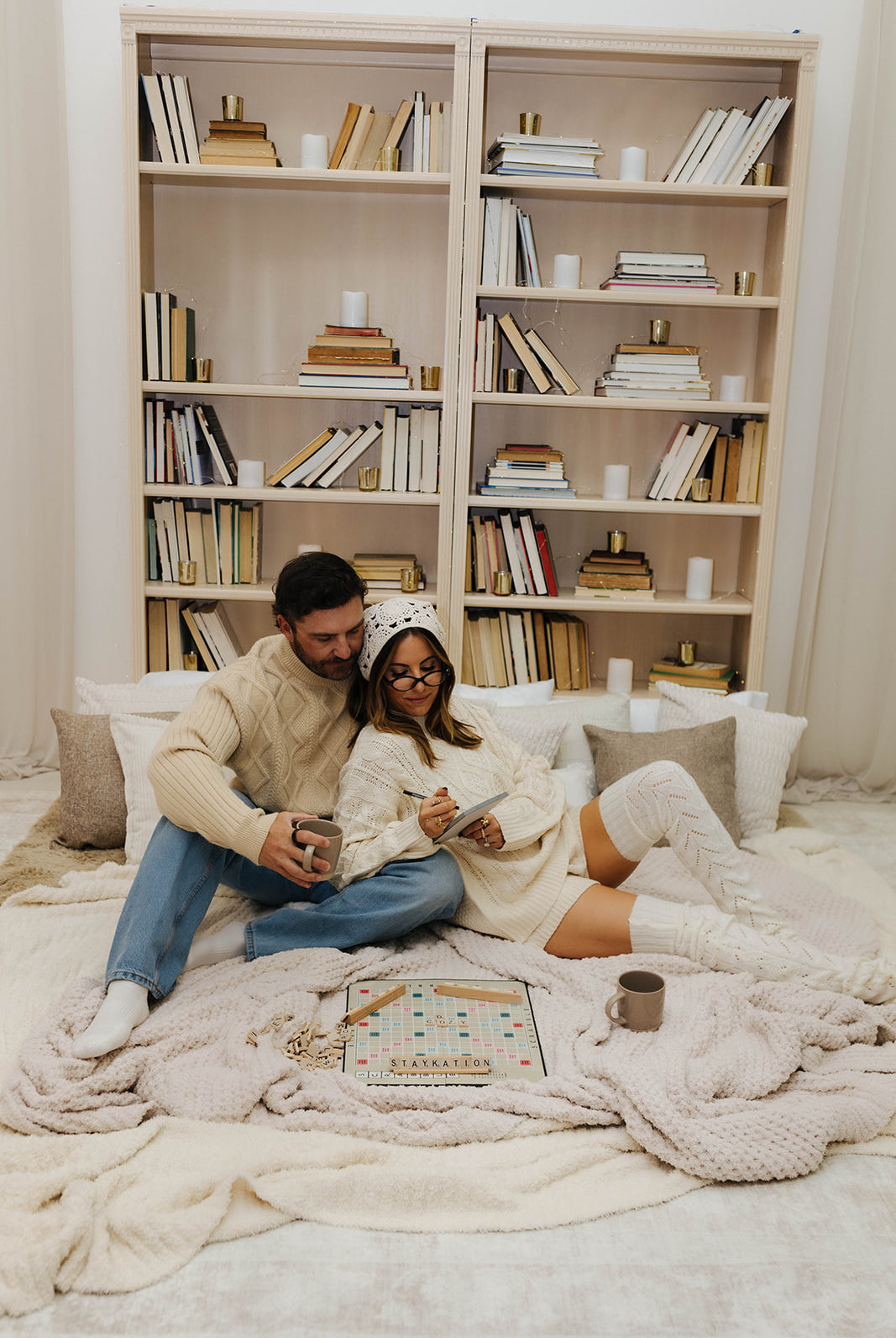 Couple sitting on cozy blankets with a bookshelf in the background
