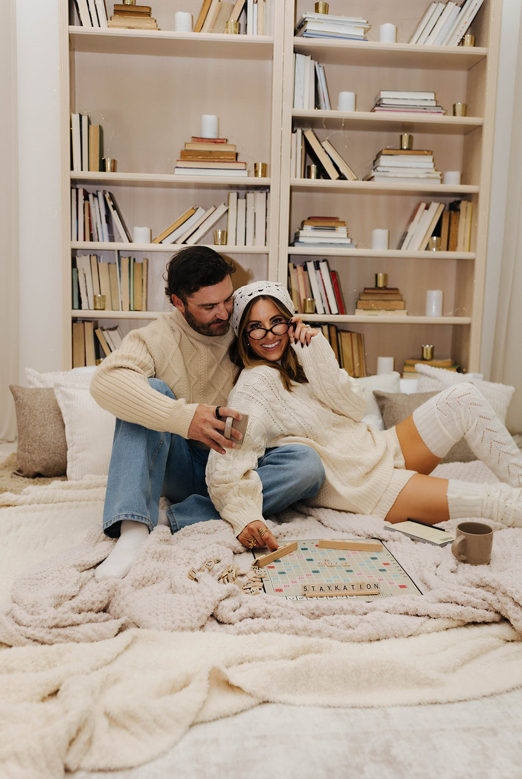 Couple sitting on a couch in a cozy living room with bookshelves in the background.