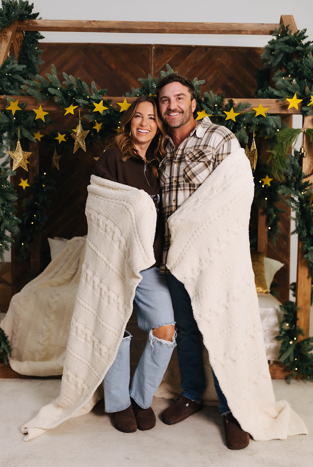 Man and woman wrapped in a blanket with Christmas decorations in the background