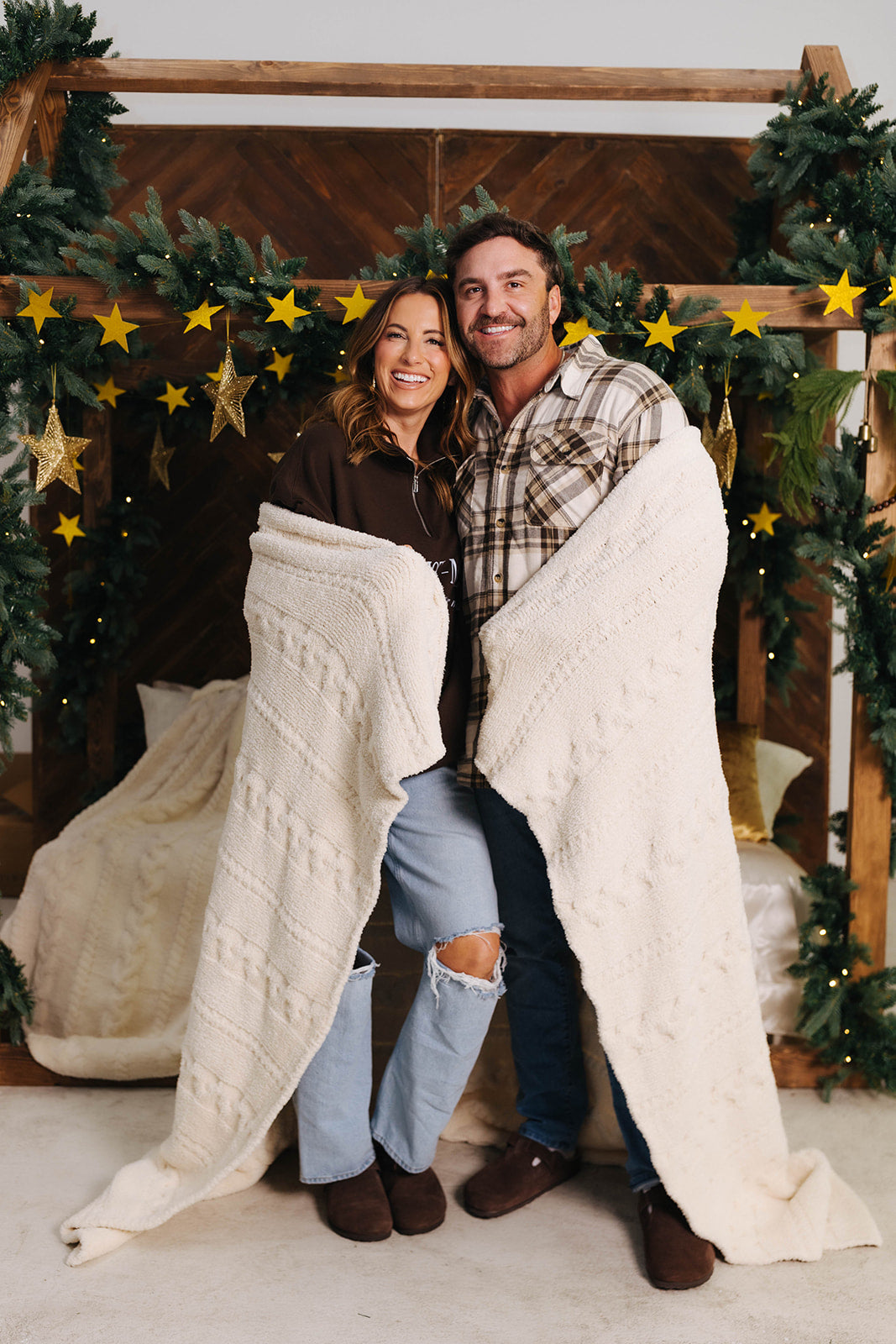 Man and woman wrapped in a blanket with Christmas decorations in the background