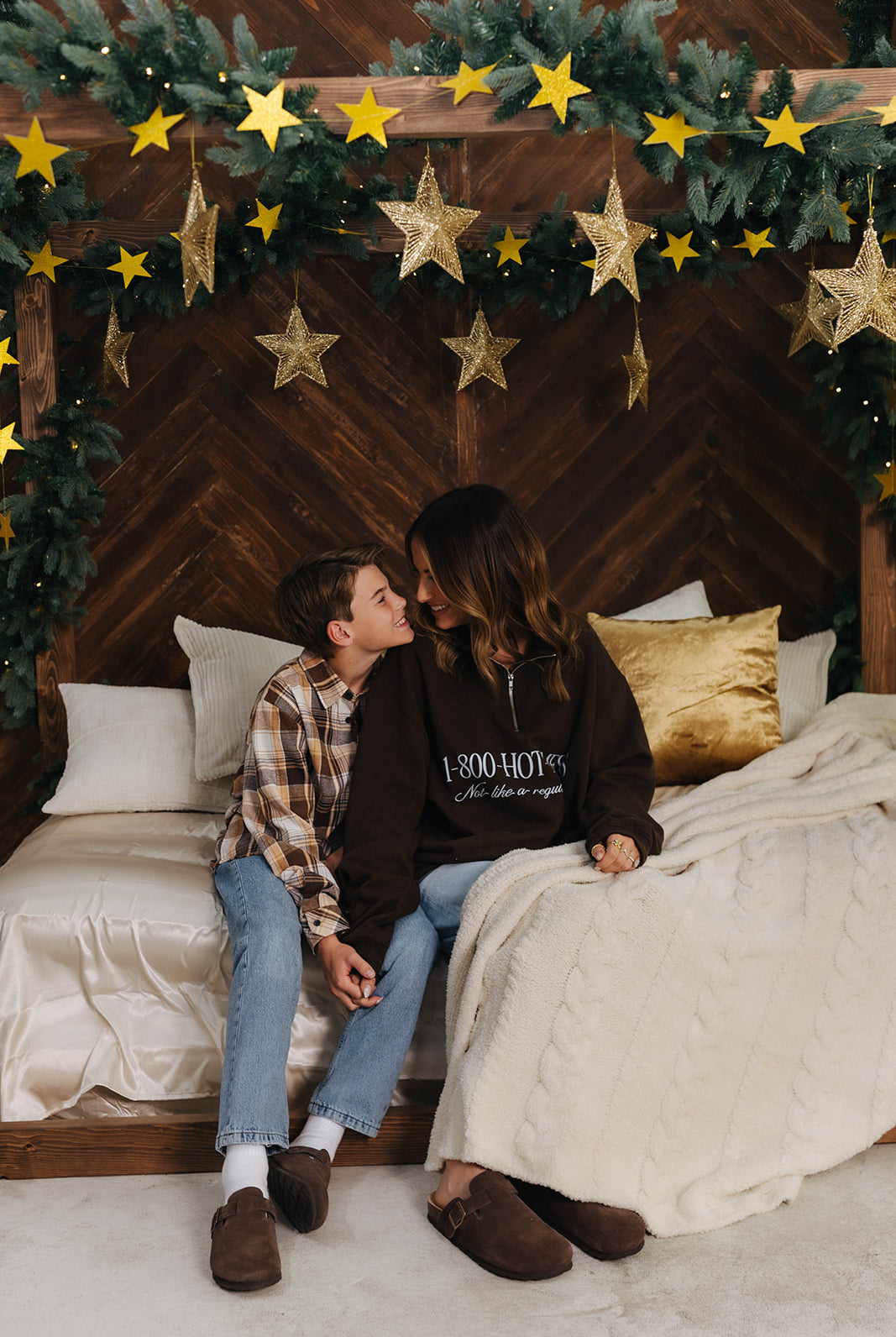 Two people sitting on a bed under a starry night sky with Christmas decorations.