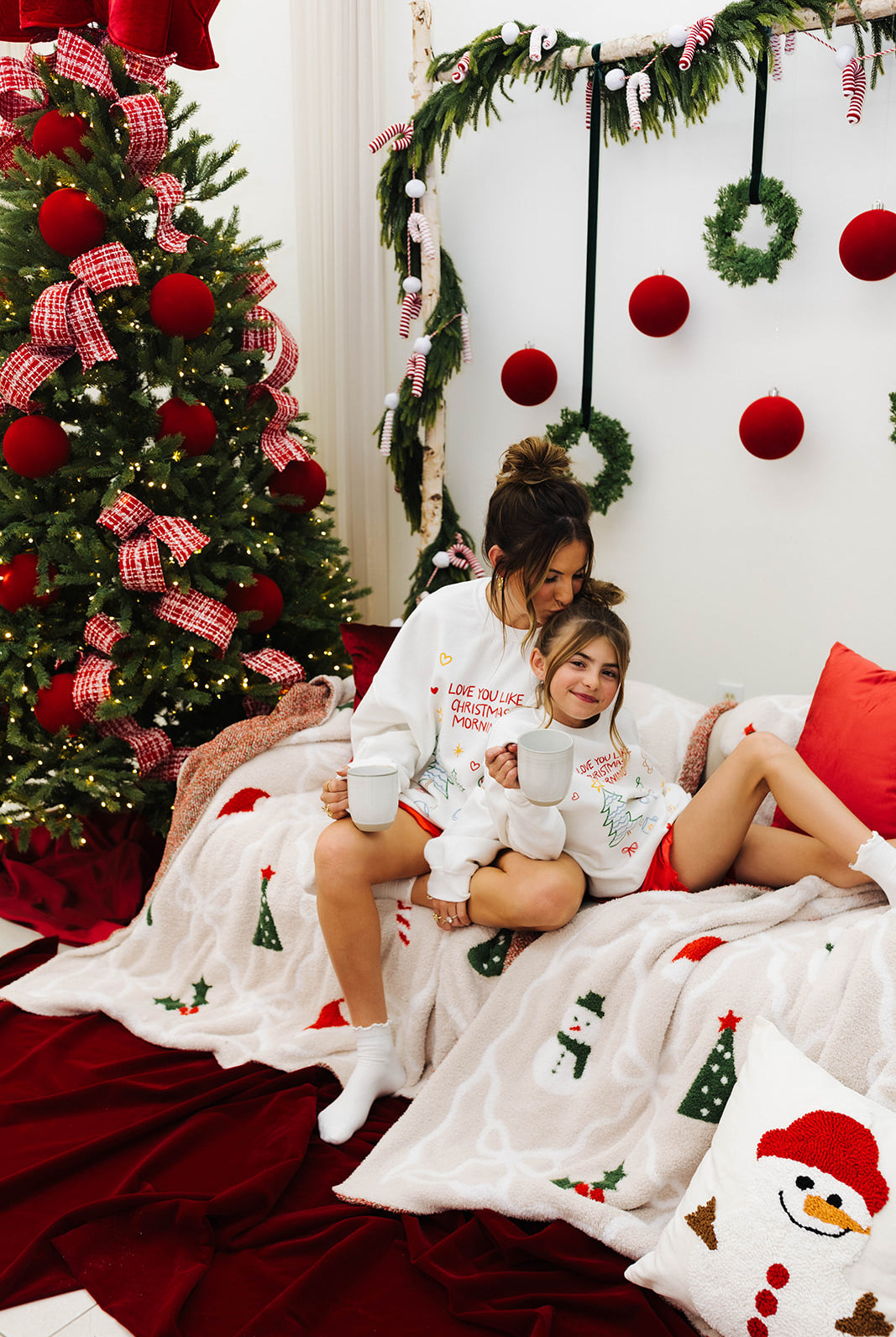 Woman and child sitting on a couch in a festive room with Christmas decorations.