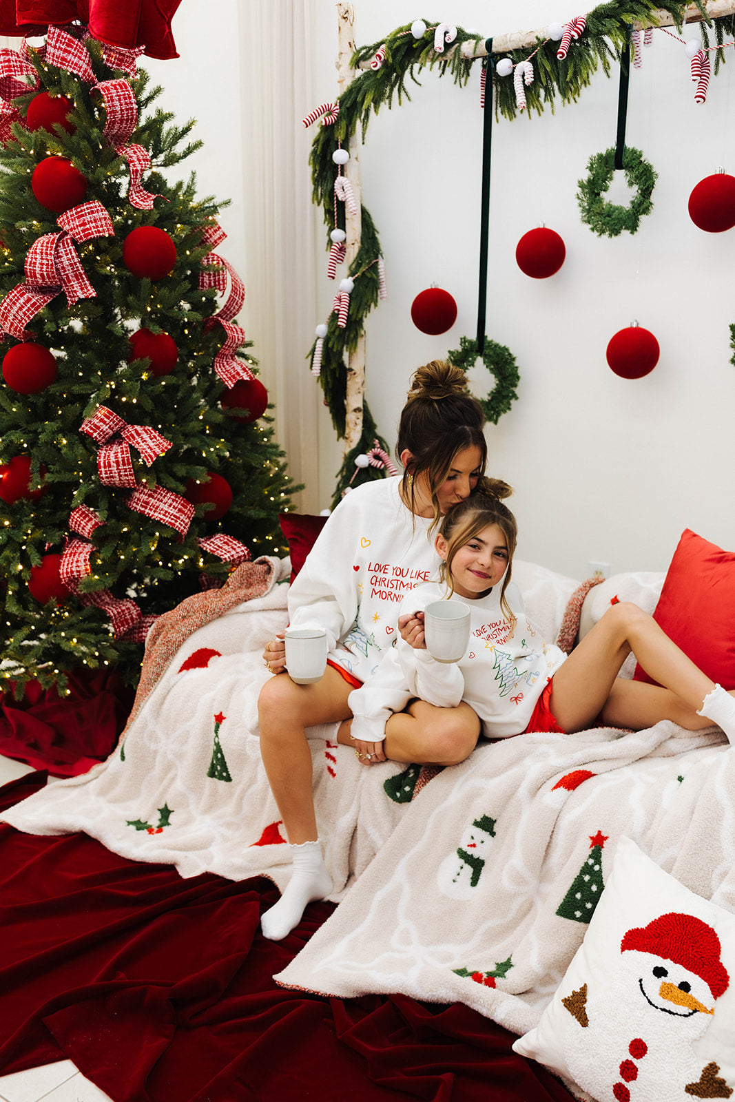 Woman and child sitting on a couch in a festive room with Christmas decorations.