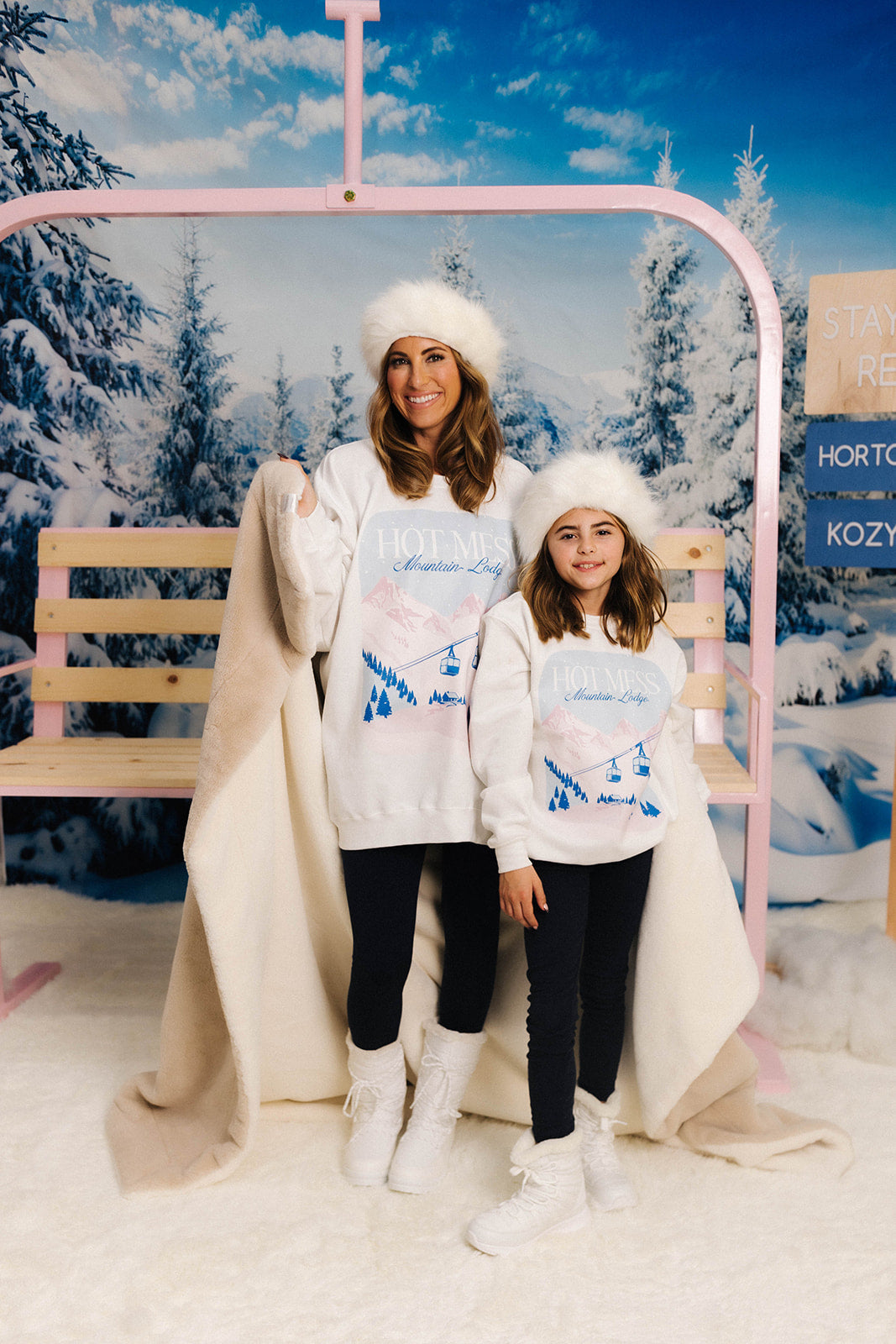 Two people in matching outfits with a snowy backdrop