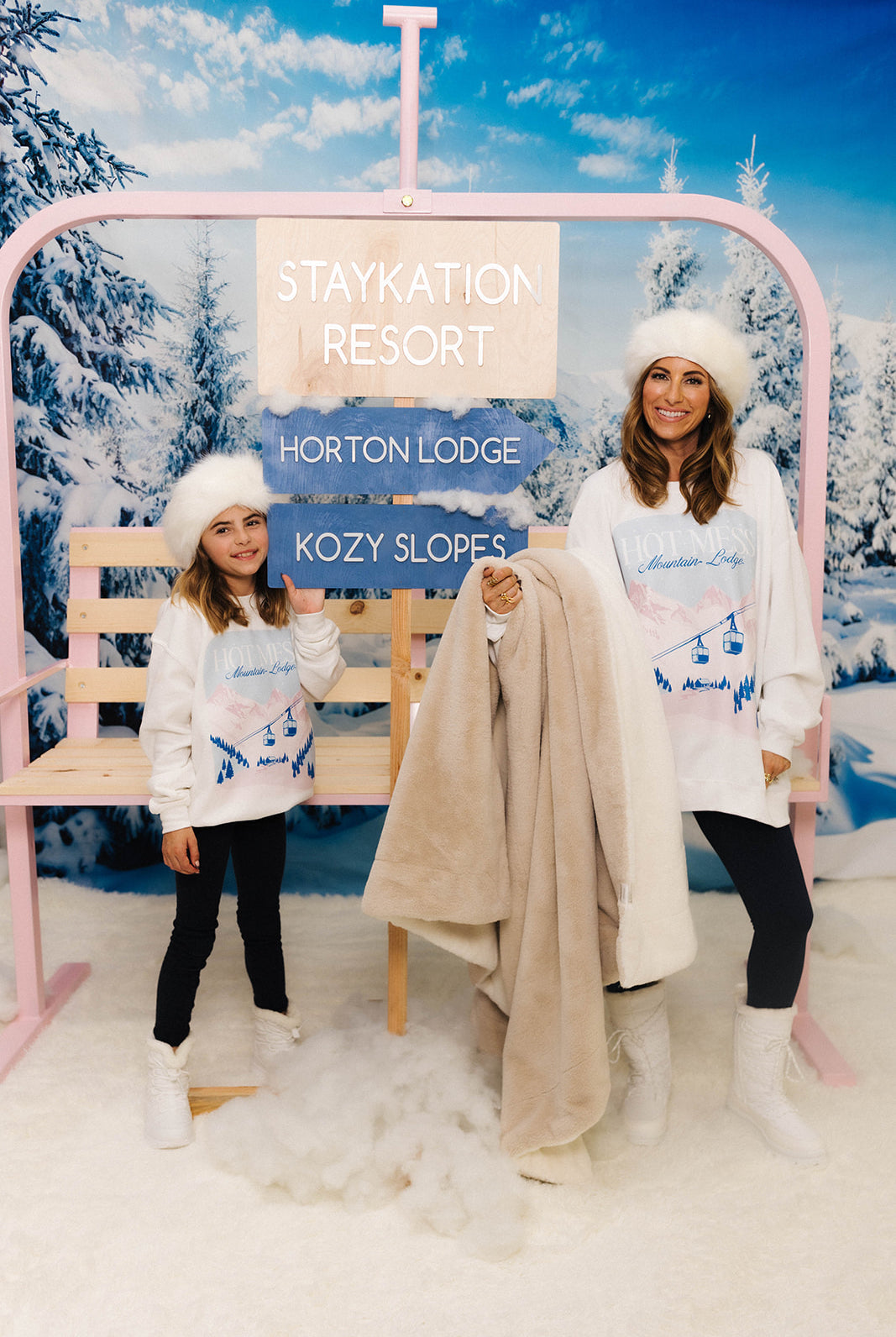 Two people in winter attire at a 'Staykation Resort' with a snowy background.