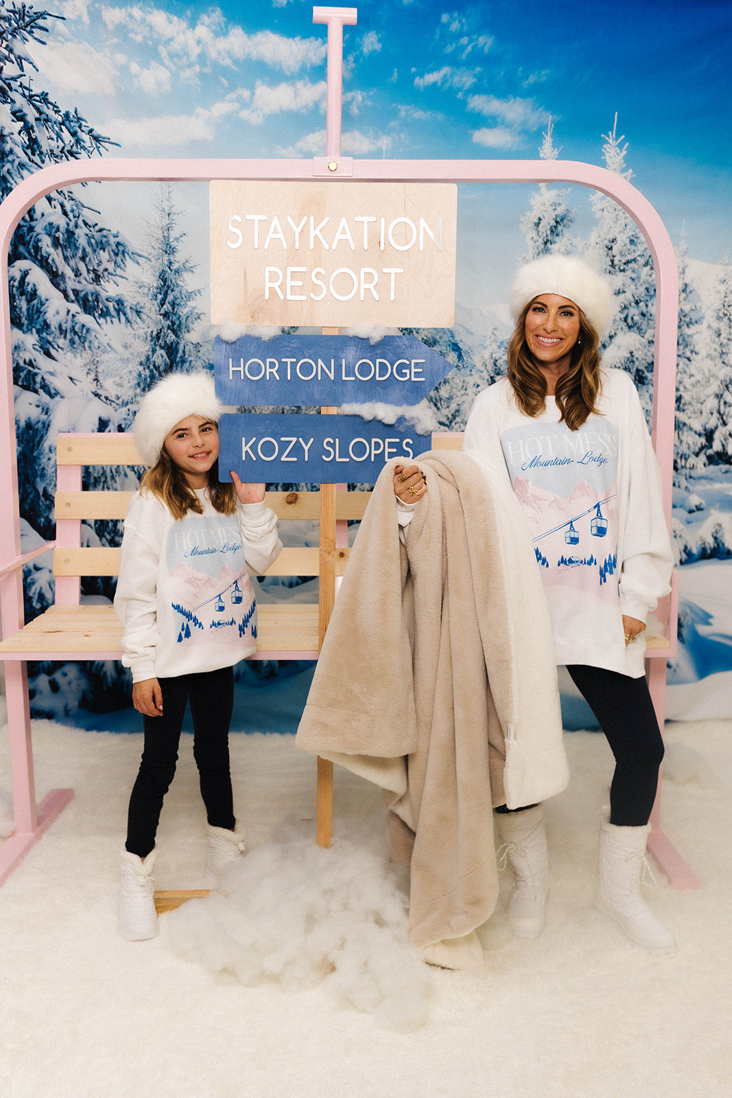 Two people in winter attire at a 'Staykation Resort' with a snowy background.