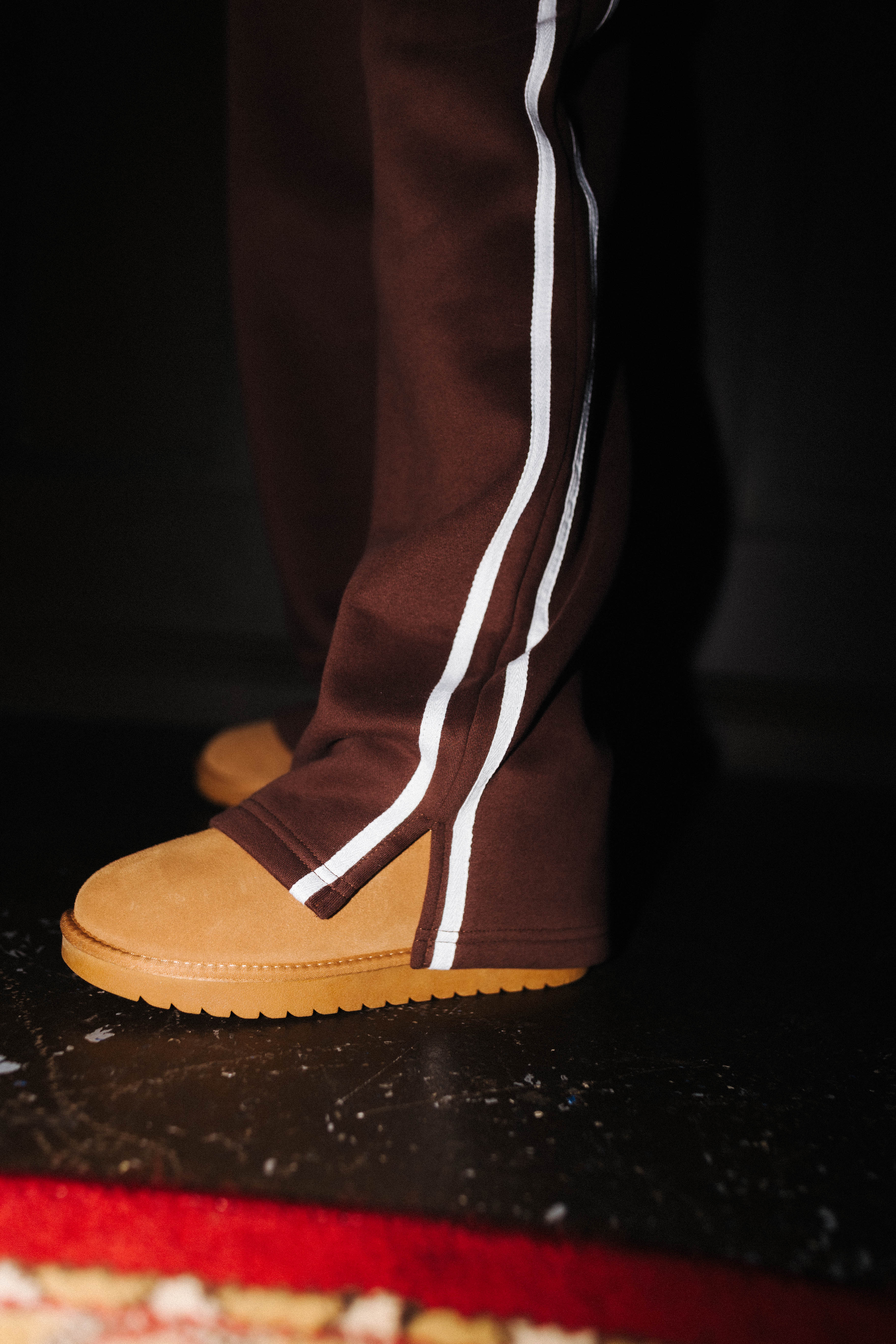 Close view of the contrasting stripes on brown sweatpants