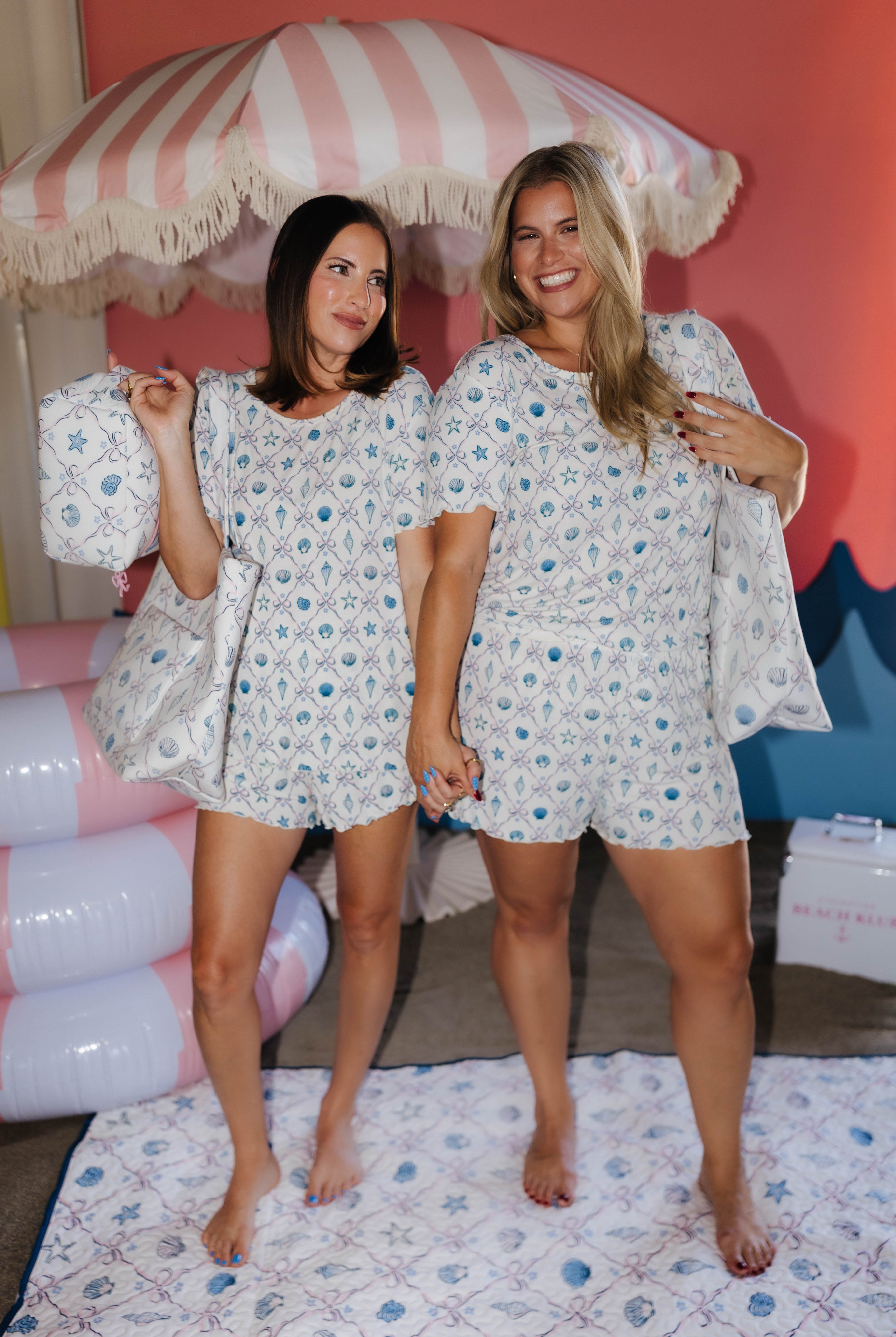 Two women wearing matching beach pjs standing in a room with colorful decor.