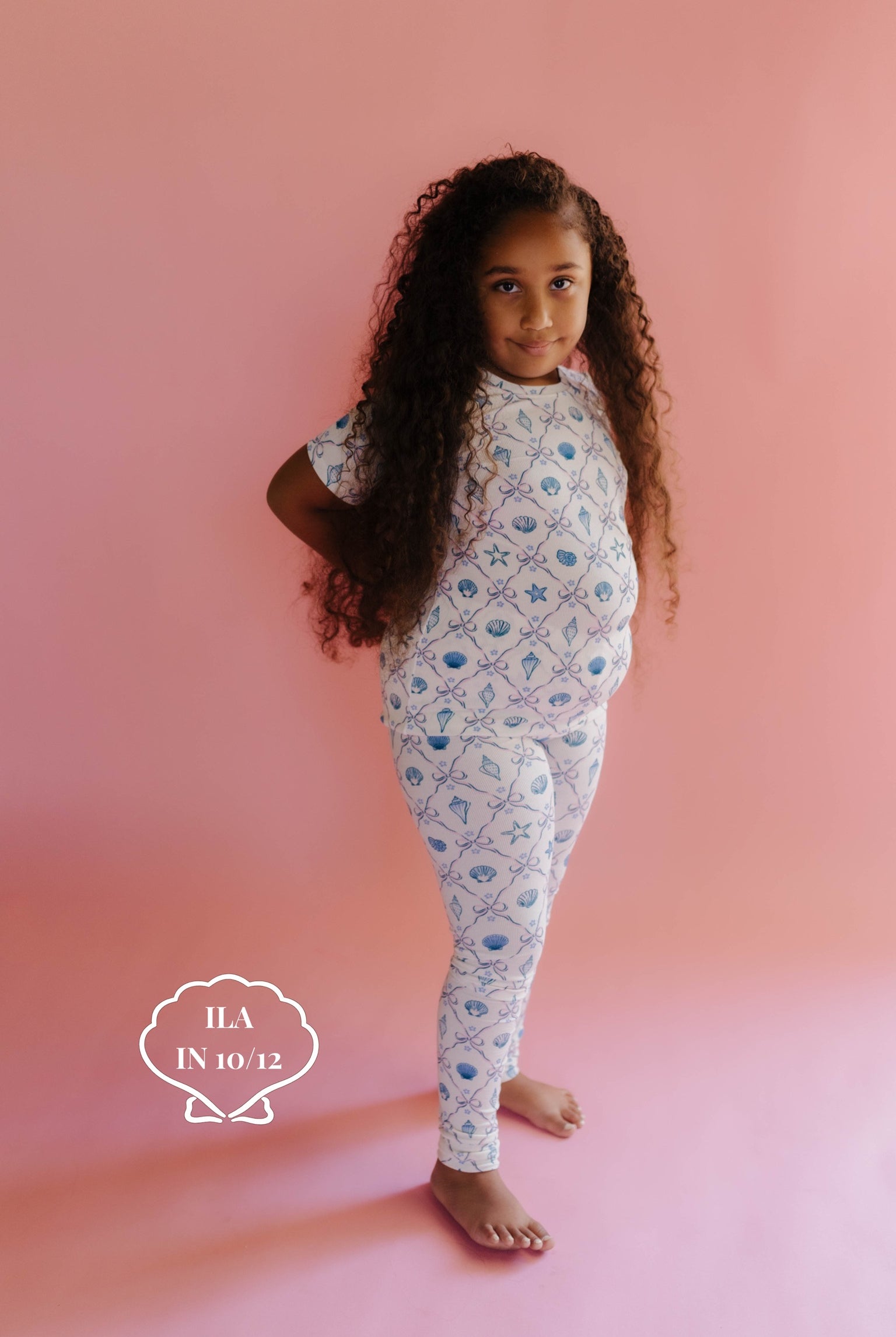 Young girl wearing a shell patterent outfit on a pink background