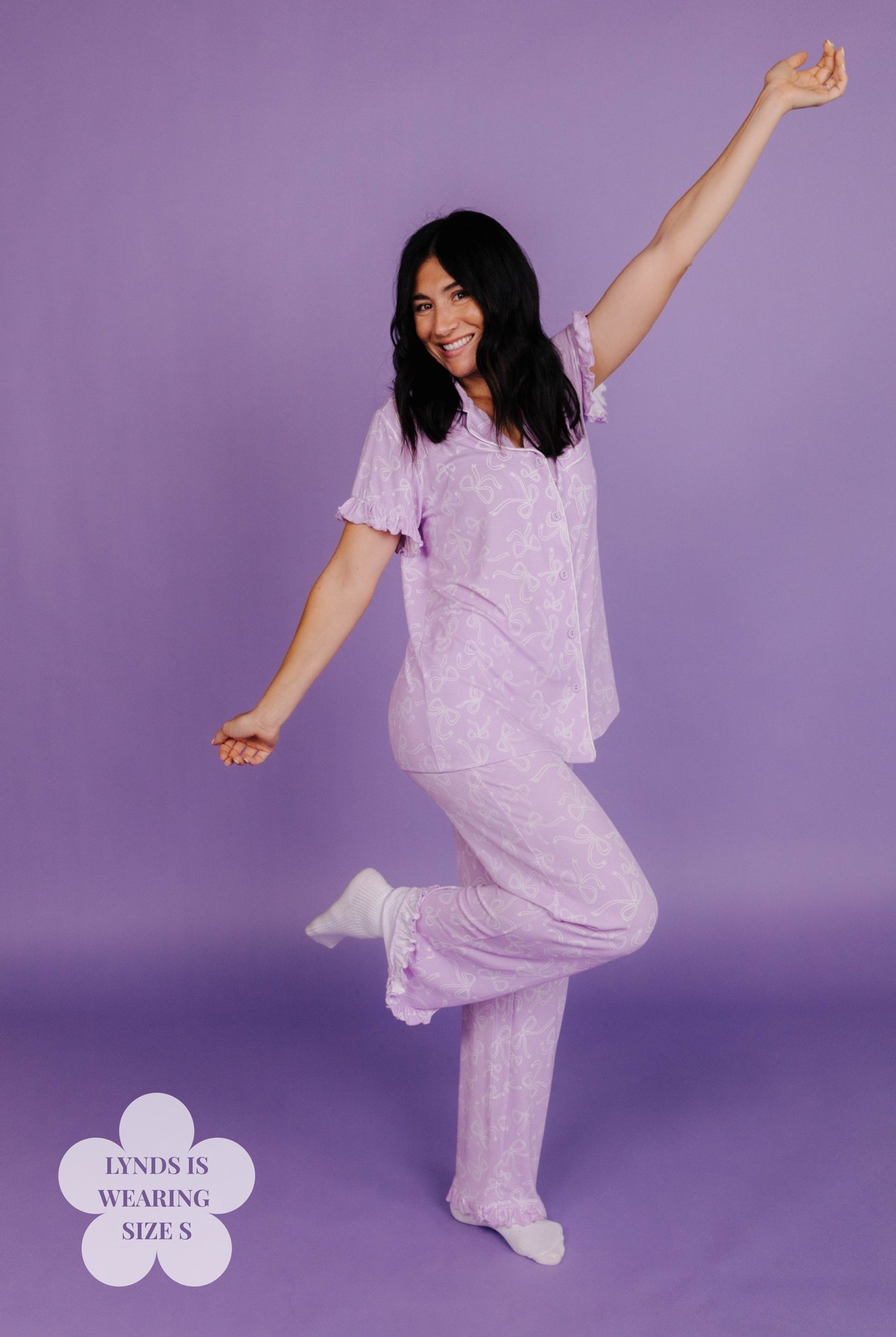 Woman in a purple pajama set posing against a purple background