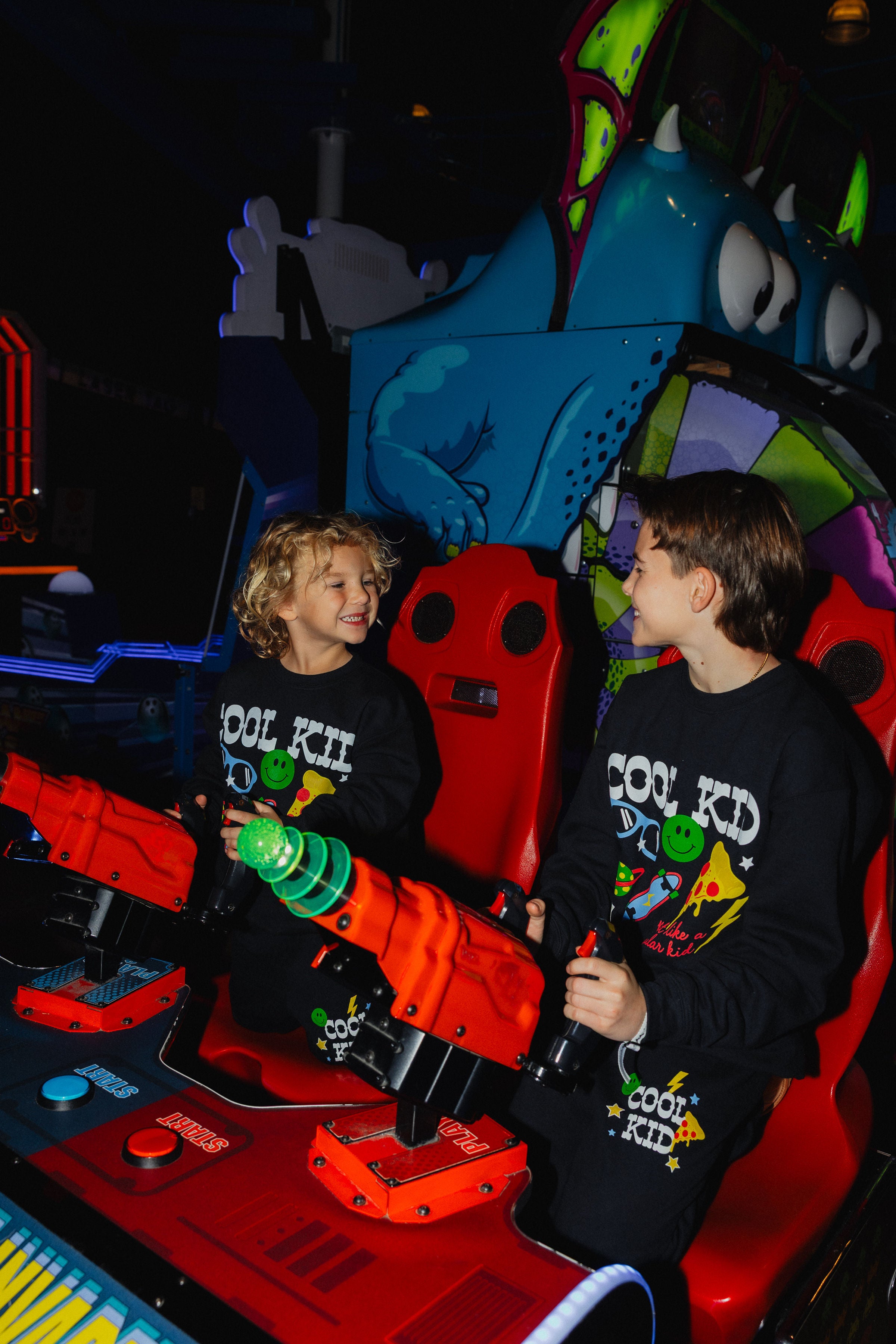 Kamp and Boss smiling at each other while playing the arcade game