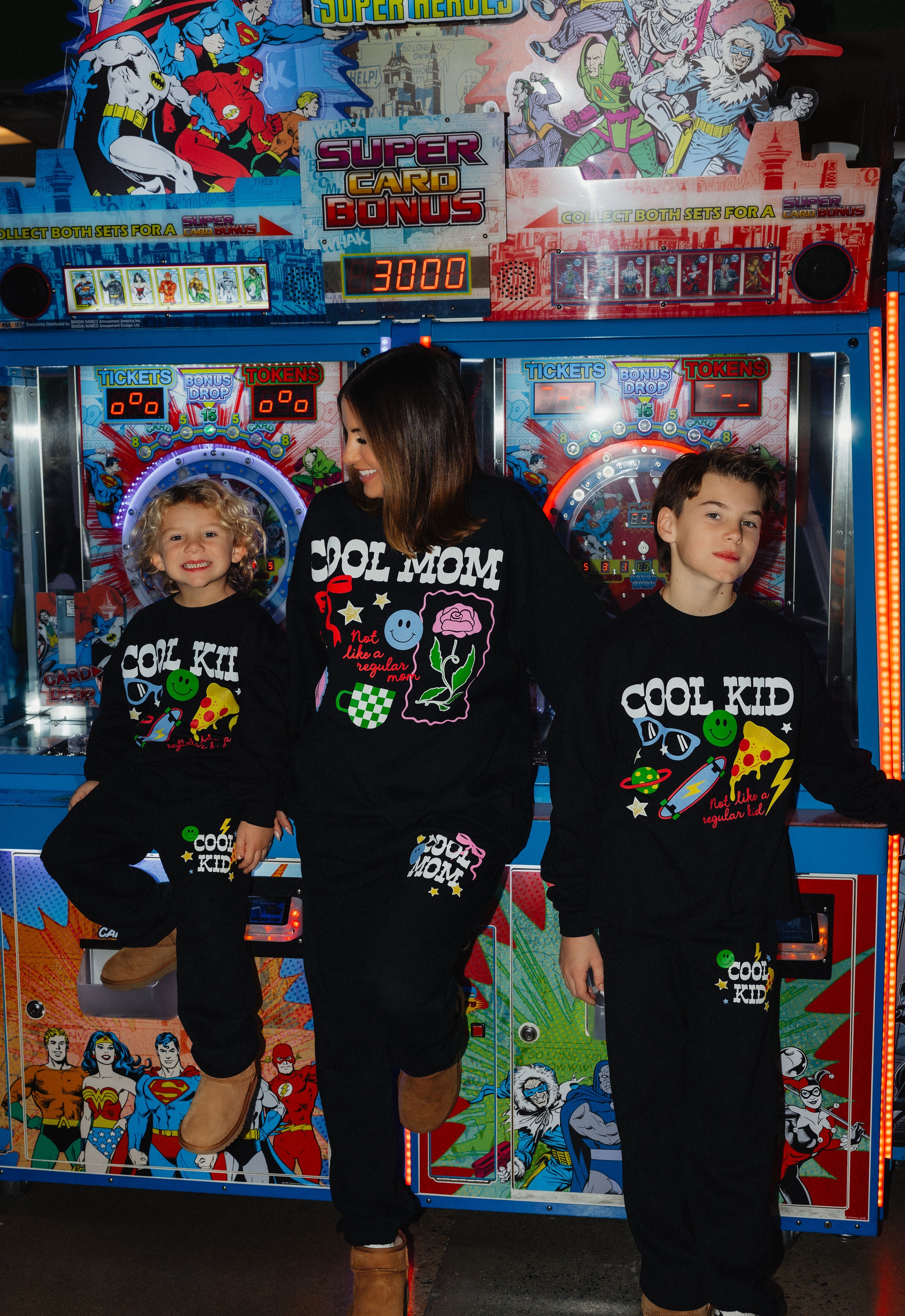 Kamp sitting on an arcade machine with Krista in the middle and boss on the side! Smiling and posing.