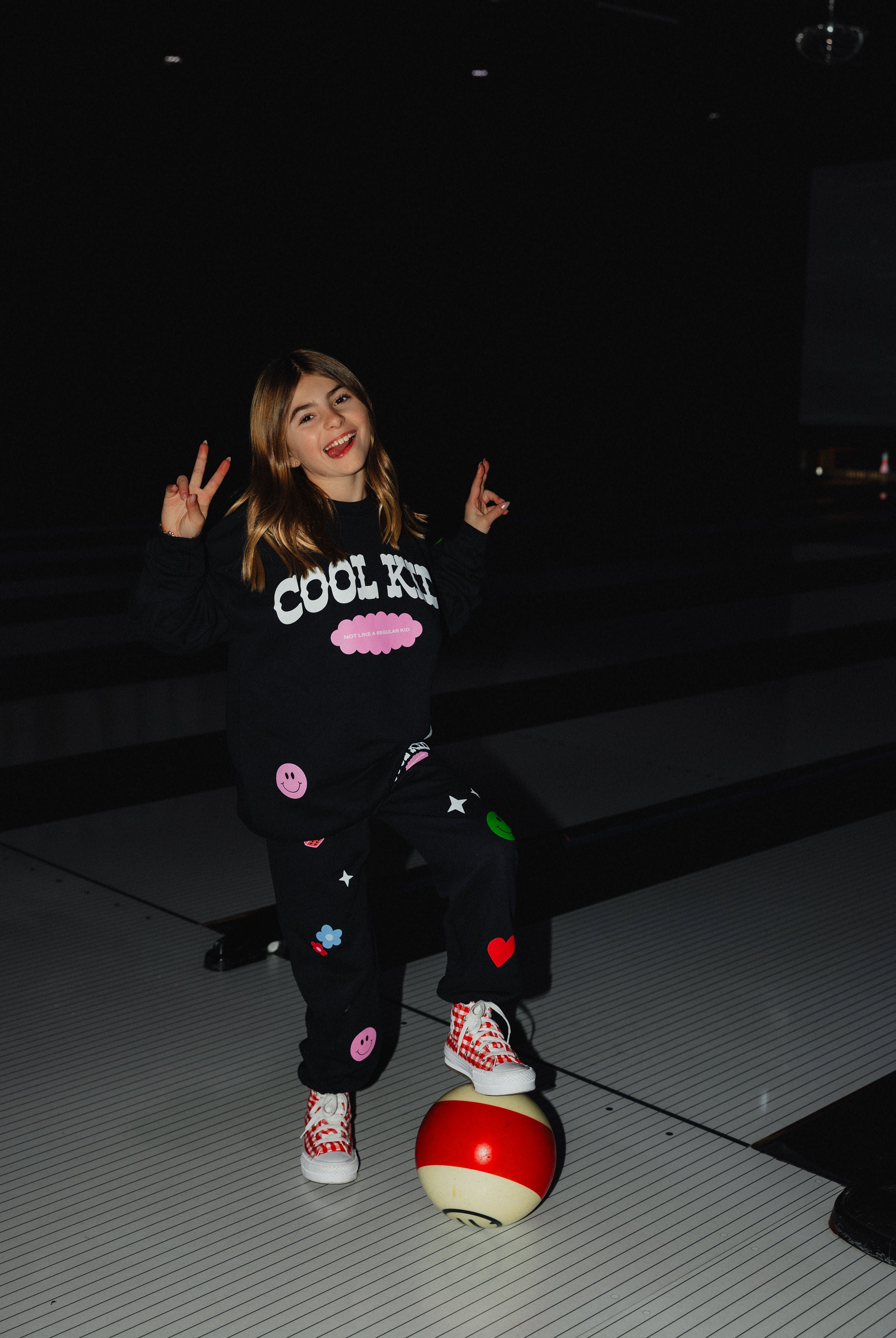 Kolly posing on the bowling ball doing peace signs