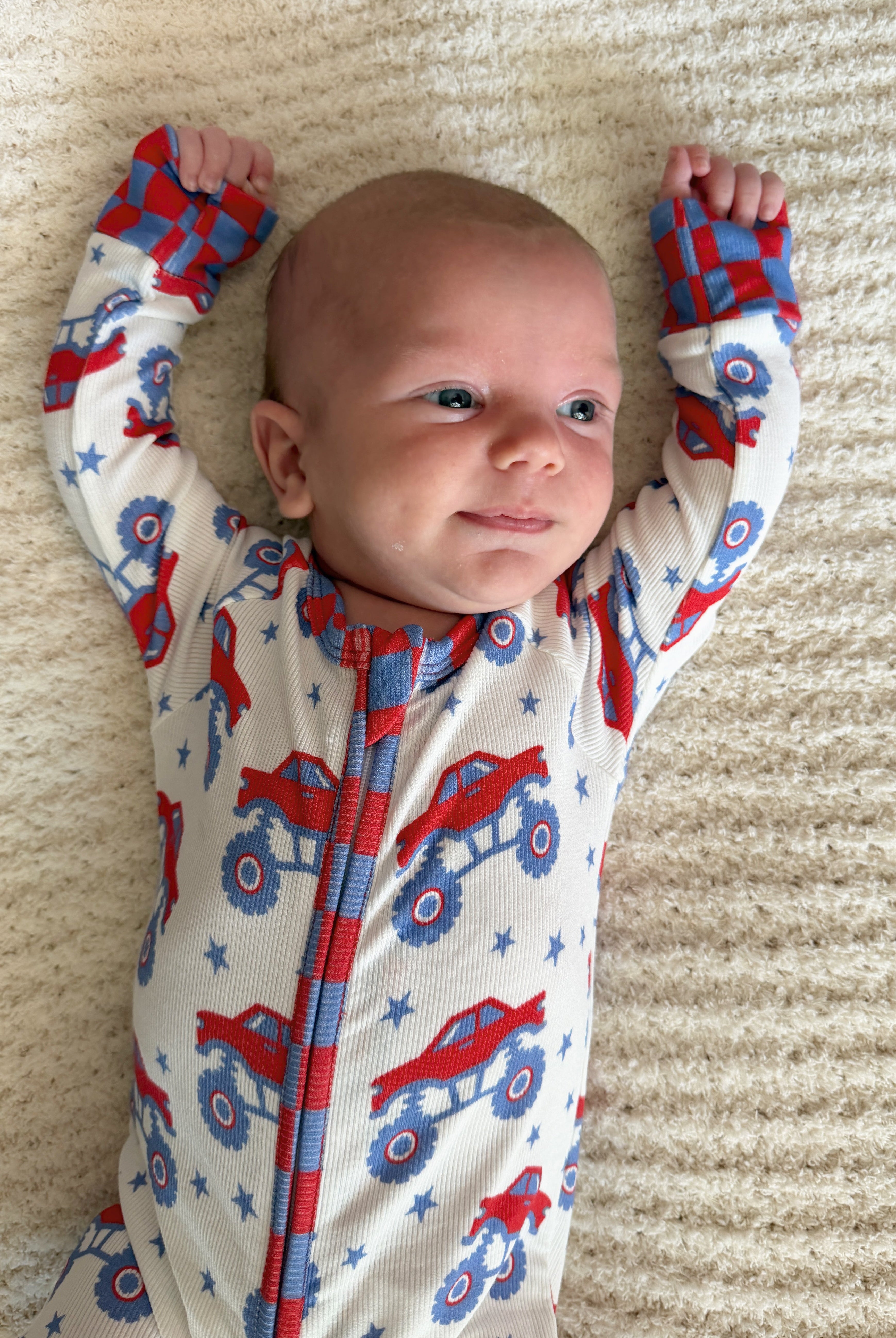 baby with arms up in monster pjs