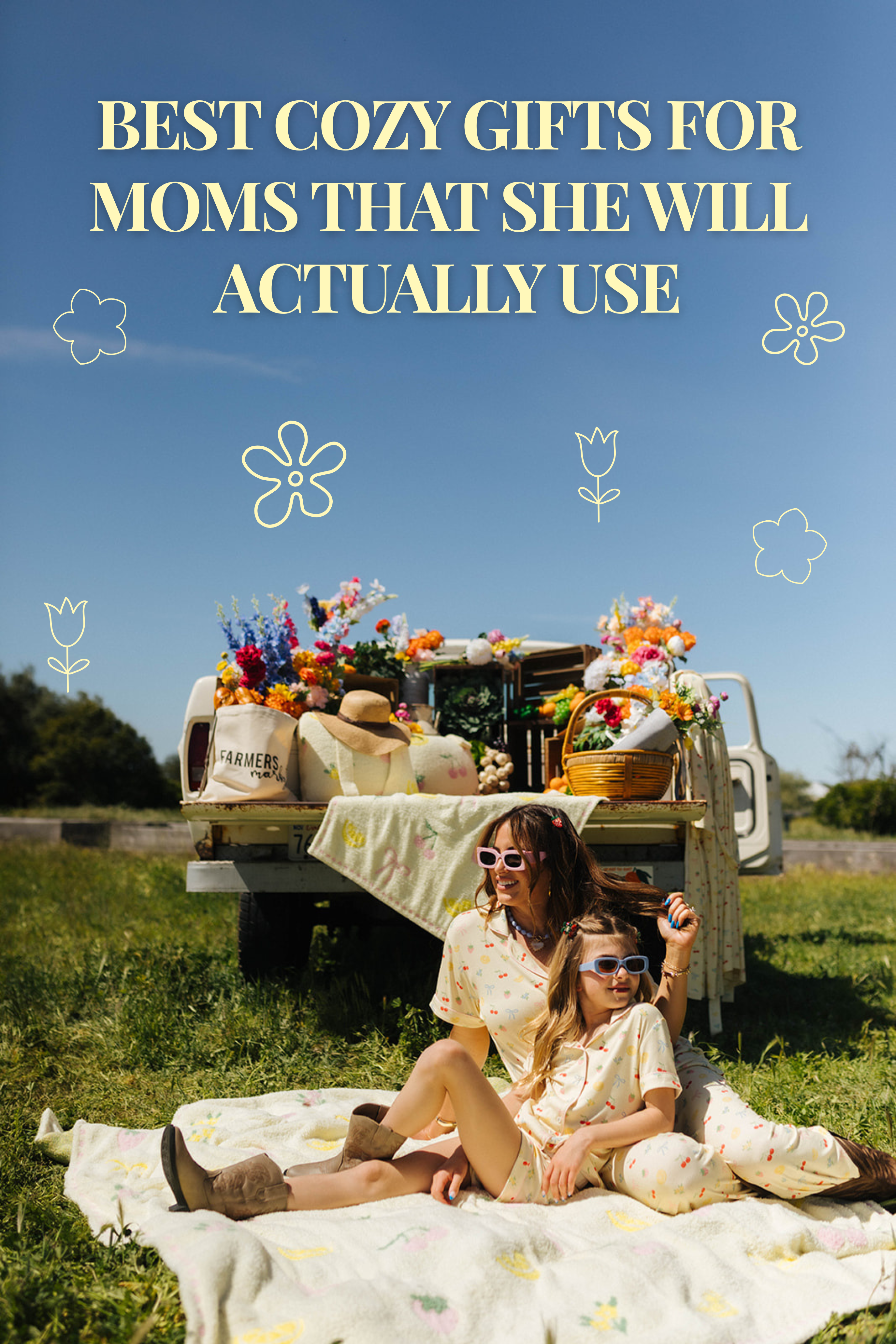 Krista and daughter sitting on a blanket in a sunny field in front of a vintage truck filled with flowers and picnic items, with the text “Best Cozy Gifts for Moms That She Will Actually Use” displayed above them.