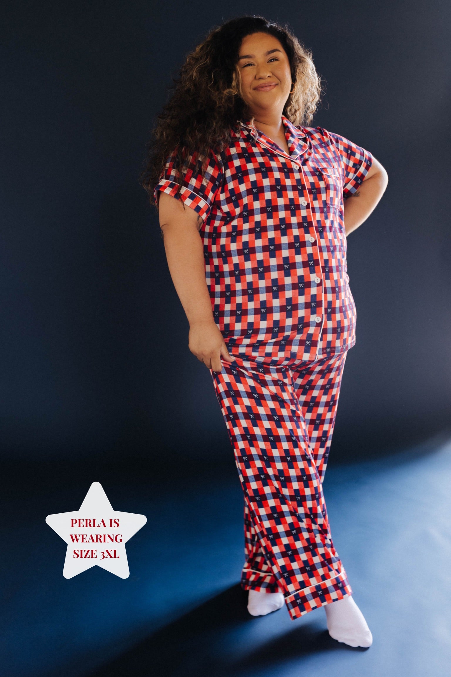 Girl wearing a red and blue gingham pj set on blue background 