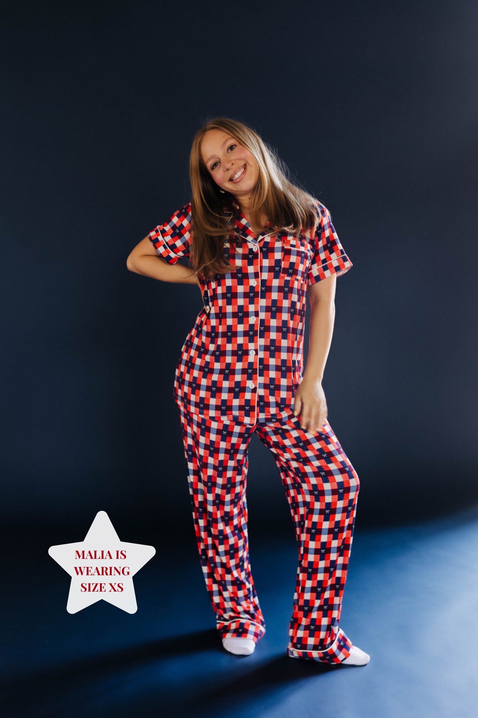 Person wearing a red and blue gingham pj set on blue background 