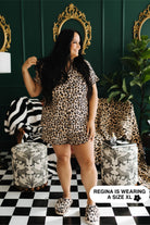 Woman wearing leopard print pjs in a stylish room with green walls and checkered floor.