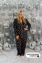 Woman wearing a black disco ball pajama set in front of a silver disco ball background