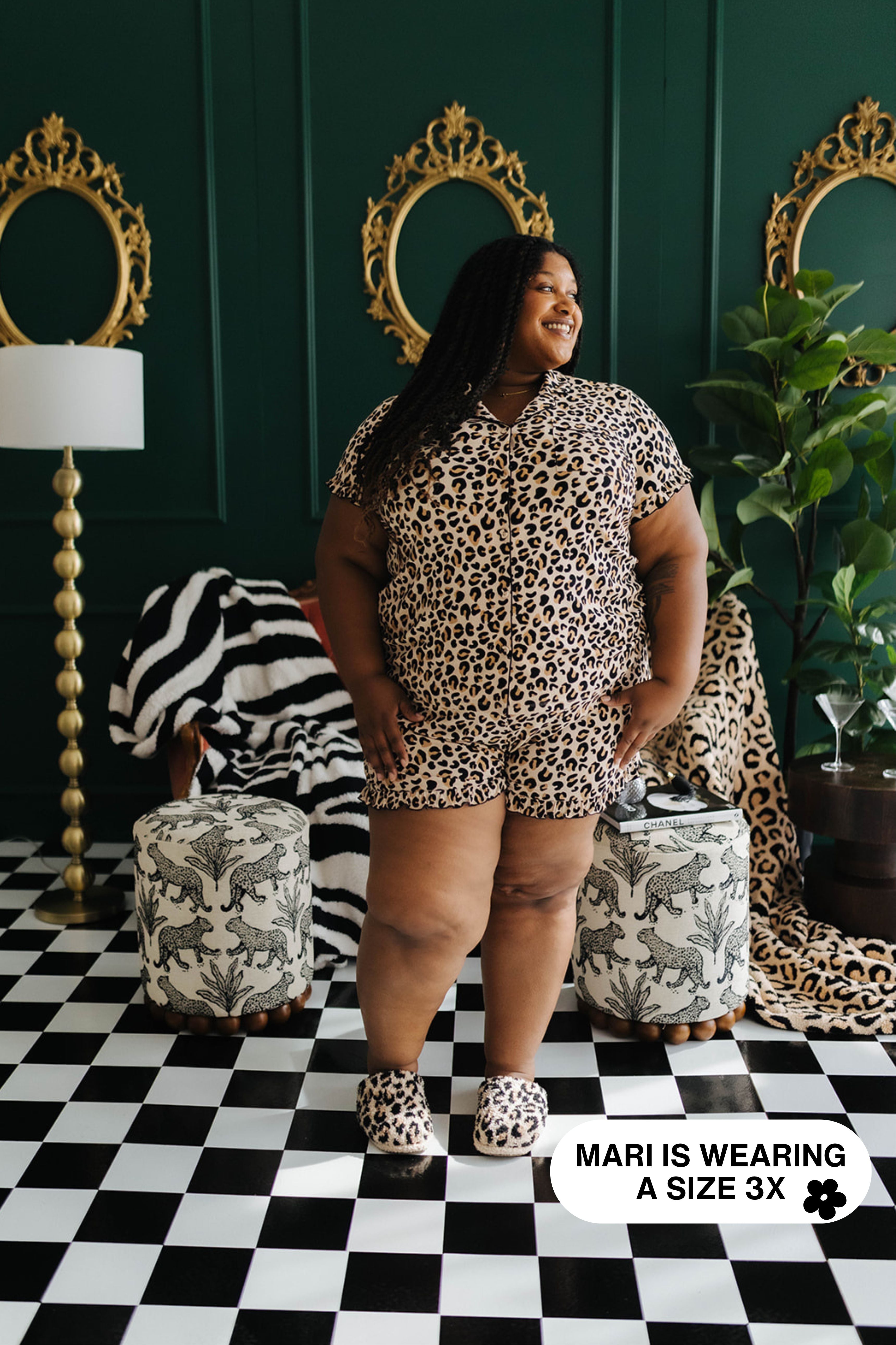 Woman wearing a leopard print outfit in a stylish room with decorative mirrors and furniture.