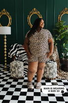 Woman wearing a leopard print outfit in a stylish room with decorative mirrors and furniture.
