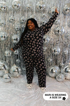 Person wearing a disco ball pajama set against a disco ball backdrop