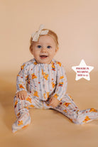 baby sitting on a cream background in teddy bear pjs 