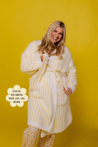 Woman wearing a yellow and white striped robe against a yellow background
