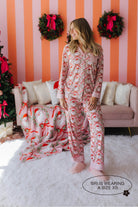 Woman wearing festive pajamas in a decorated living room with Christmas decorations.