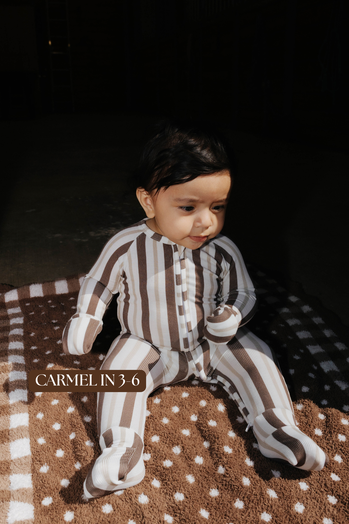 Sizing photo: Carmel in 3-6 months wearing brown and cream striped baby zip pajamas.
