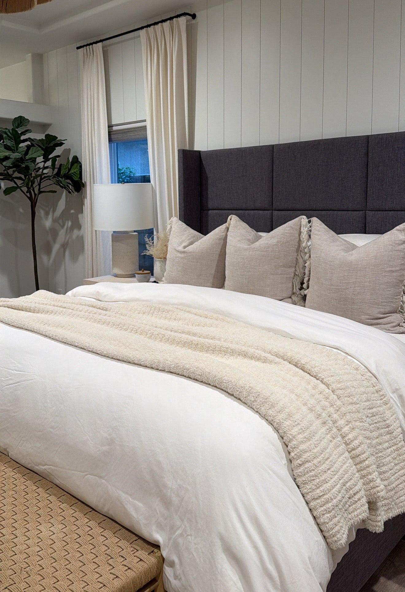 Neatly made bed with white bedding and beige pillows in a bedroom setting.