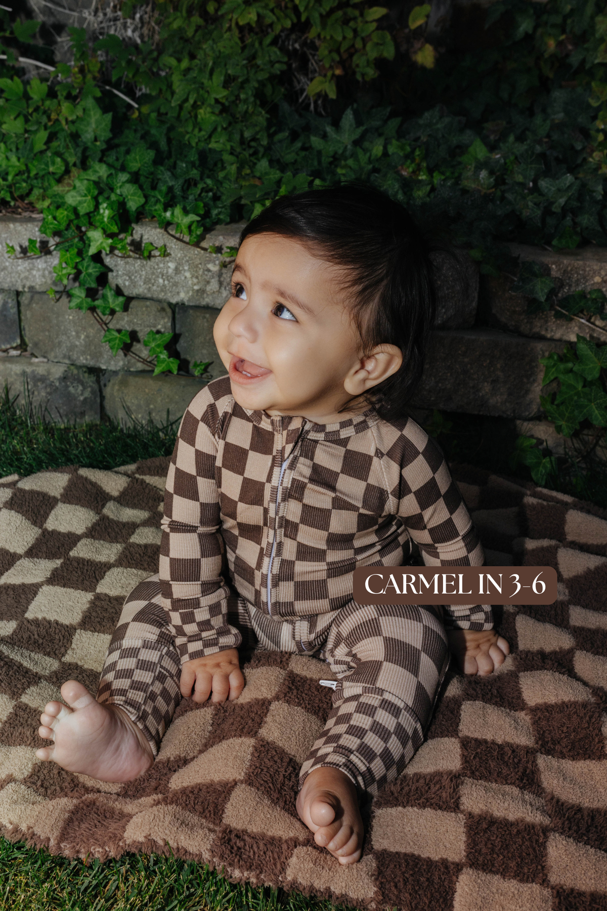 Sizing photo: Carmel in 3-6 months wearing brown check baby zip pajamas.