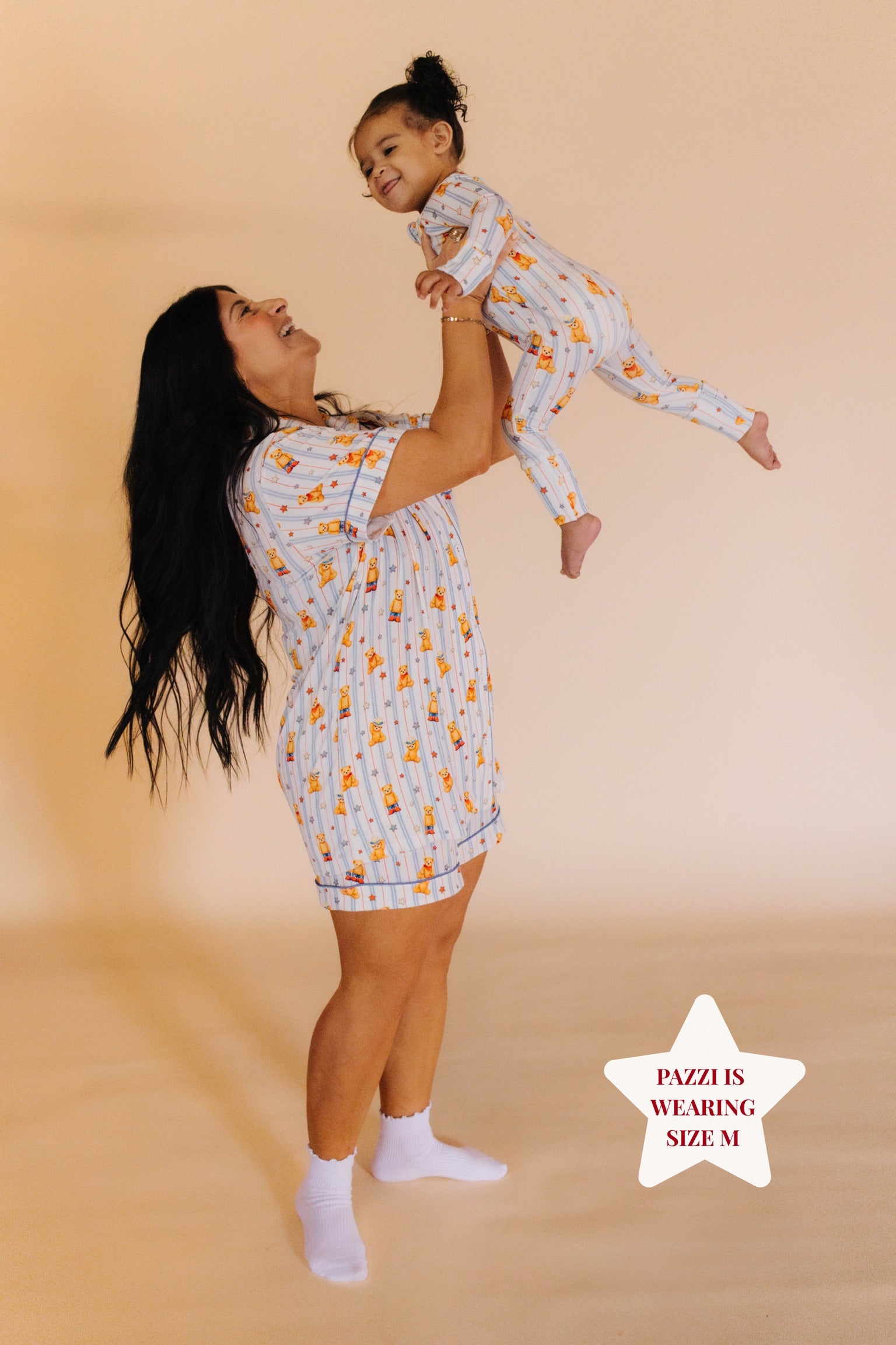 Mom holding daughter in the air in matching pjs 
