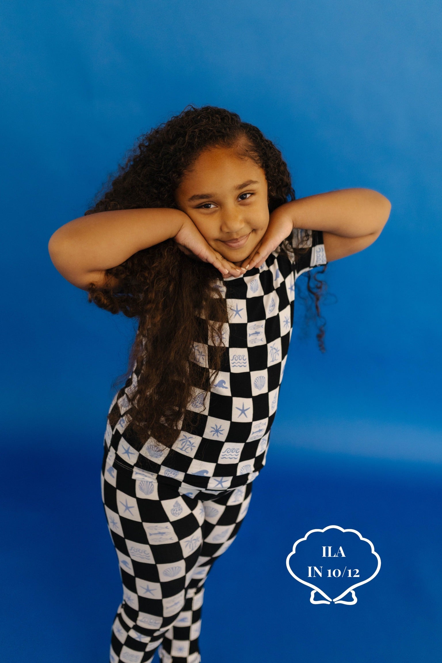 Child wearing a black and white checkered pj set on a blue background size 10/12