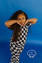 Child wearing a black and white checkered pj set on a blue background size 10/12