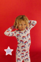 Child wearing pajamas with truck pattern on a red background