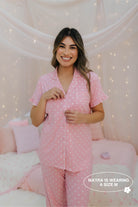 Woman wearing pink polka dot pajamas in a cozy room with soft lighting.